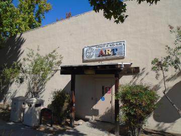 Sign reading Fine Arts above shaded entrance with surrounding greenery.