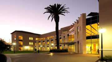 Lucas Hall building illuminated at dusk with palm tree in the foreground.