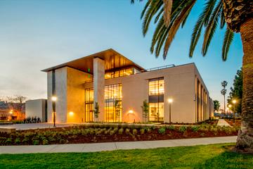 A modern building labeled Charney Hall with palm trees.