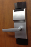 Silver SecurAll/Onity door lock and handle on a wooden door.