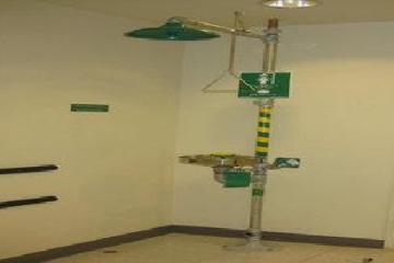 Industrial eye wash and safety shower station in a plain room.