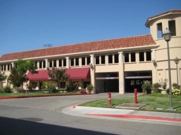 Parking Structure with tan walls, red awnings, and landscaped area in front.